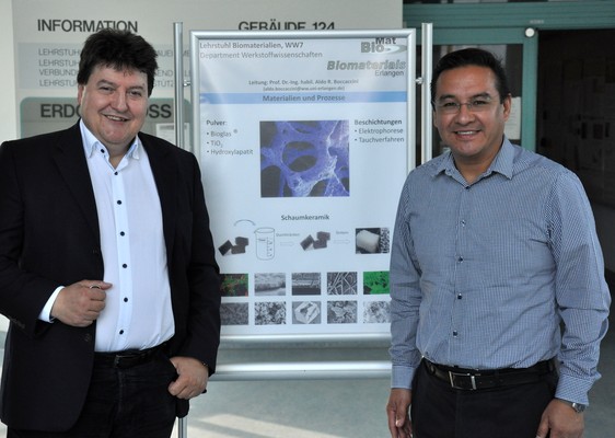 Professor Boccaccini zusammen mit Professor Juan Muñoz Saldaña, vor einem Poster über bioaktive Gläser.