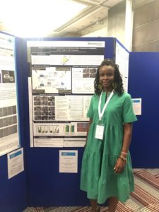 Hazel standing next to her poster at the conference.