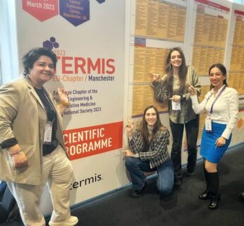 The members of the institute standing next to the conference banner.