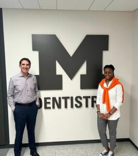 Prof. Bottino and Hazel standing next to the sign of University of Michigan's Dentistry.