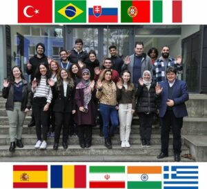 Prof. Boccaccini standing with visitors outside the institute. The flags of the participating countries appear on the top and bottom of the image.