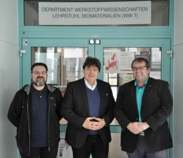 Prof. Boccaccini, Prof. Čelko and Dr. Gejdoš standing in front of the entrance to the institute, looking at the camera, smiling.