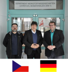 Prof. Boccaccini, Prof. Čelko and Dr. Gejdoš standing in front of the entrance to the institute, looking at the camera, smiling.