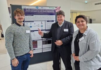 Prof. Aldo R. Boccaccini, Dr. Irem Unalan, and Markus Lorke smiling in front of the poster
